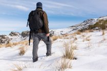Jovem com uma mochila caminhadas desfrutando nas montanhas nevadas em um dia ensolarado de inverno. — Fotografia de Stock