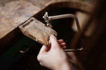 Обрізати крупним планом руки людини різьблення прикраси шматка дерев'яної кори з інструментом на стіл — стокове фото