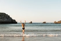 Silhouette di donna in piedi in mare con le braccia alzate — Foto stock