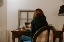 Giovane donna digitando sul computer portatile al tavolo vintage — Foto stock