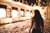 Очаровательная молодая женщина стоит под украшенной крышей светлого павильона и смотрит вниз — стоковое фото