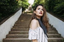 Elegant thoughtful woman standing against stairs in park — Stock Photo