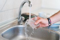 Crop hand of unrecognizable person washing glass in sink on kitchen. — Stock Photo