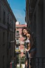 Menina encantadora em roupa interior e botas com jaqueta em pé na varanda e sorrindo para a câmera à luz do sol — Fotografia de Stock