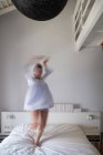 Donna offuscata che salta sul letto — Foto stock