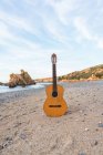 Guitarra acústica clássica colocada no oceano em uma praia. — Fotografia de Stock