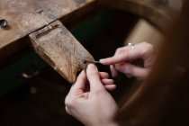 Обрезание крупными руками женской резьбы и чистка мелких деталей кисточкой за столом — стоковое фото