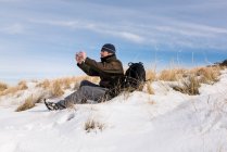 Wanderer mit Handy in verschneiten Bergen an einem sonnigen Wintertag. — Stockfoto