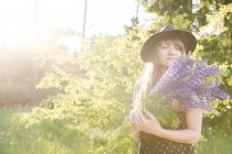 Donna con fiori in sole lucente — Foto stock