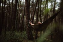 Person liegt in grüner Hängematte unter Bäumen im Wald in Kantabrien, Spanien — Stockfoto