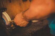 Crop smith usando grindstone para afiar lâmina de metal na oficina profissional — Fotografia de Stock