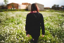 Молода жінка в чорному, що стоїть на газоні з жовтими квітами — стокове фото