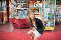 Jeune femme heureuse tournant autour dans la rue contre magasin de parc d'attractions — Photo de stock