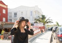 Giovane donna in elegante cappello passeggiando sulla strada della località turistica — Foto stock