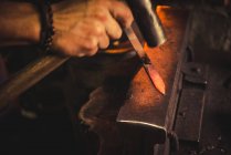 Homme anonyme utilisant hummer pour forger la lame à partir de morceau de métal dans l'atelier professionnel — Photo de stock