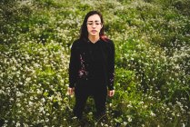 Elegante giovane donna con gli occhi chiusi in piedi in campo verde con fiori bianchi — Foto stock