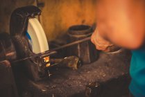 Кузнец использует шлифовальный камень для резки металлического лезвия в профессиональной мастерской — стоковое фото