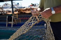 Урожай сверху вид человека, держащего в руках рыболовные сети и режущего ножом — стоковое фото