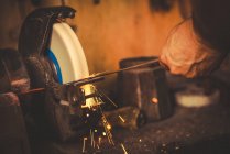 Обрізати коваля за допомогою щебеню, щоб загострити металеве лезо в професійній майстерні — стокове фото