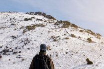 Young man with a backpack hiking enjoying in the snowy mountains on a winter sunny day. — Stock Photo