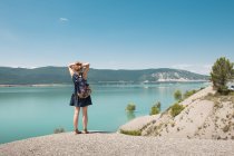 Женщина с рюкзаком стоит на живописном море и смотрит на вид — стоковое фото