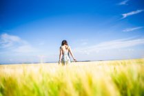 Chica de pie en el campo en un día soleado - foto de stock