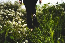 Pernas femininas na grama verde com flores brancas — Fotografia de Stock
