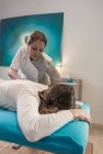 Therapeutin massiert Frau auf Tisch im Massageraum — Stockfoto
