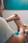 Terapeuta massageando o pé feminino na sala de massagem — Fotografia de Stock