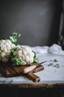 Fresh ripe cauliflowers on wooden chopping board with knife — Stock Photo
