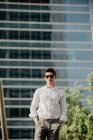 Впевнений молодий бізнесмен стоїть перед сучасною будівлею — стокове фото