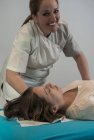 Усміхнений терапевт масажує жінку на столі в масажному кабінеті — стокове фото