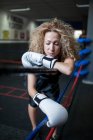 Mulher adulta em luvas de boxe encostada ao ringue — Fotografia de Stock