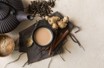 Taza oriental de té Chai con leche, canela, jengibre, pimienta blanca y cardamomo en la superficie beige - foto de stock