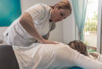Therapeutin massiert weiblichen Rücken auf Tisch im Massageraum — Stockfoto