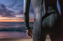 Triatleta in costume in neoprene in piedi sulla spiaggia all'alba — Foto stock