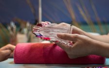 Женские руки держат красочную палитру лака для ногтей в салоне красоты — стоковое фото