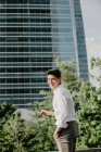 Ridendo giovane uomo d'affari in piedi contro edificio moderno e guardando oltre le spalle — Foto stock