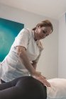 Terapeuta masajeando lomos femeninos en sala de masajes - foto de stock