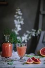 Fresh grapefruit juice in glass with ingredient on kitchen table — Stock Photo