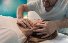 Terapeuta massaggiando viso femminile in sala massaggi — Foto stock