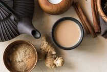 Orientalische Tasse Tee Chai mit Milch, Zimt, Ingwer, weißem Pfeffer und Kardamom auf beiger Oberfläche — Stockfoto