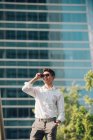 Uomo d'affari positivo in piedi contro l'edificio moderno — Foto stock