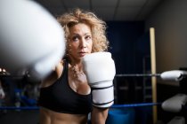 Entrenamiento de mujer seria en gimnasio con saco de boxeo - foto de stock