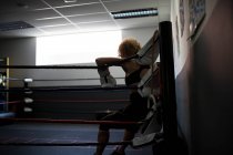 Mulher adulta em luvas de boxe encostada ao ringue — Fotografia de Stock