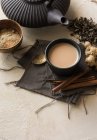 Xícara de chá oriental Chai com leite, canela, gengibre, pimenta branca e cardamomo na superfície bege — Fotografia de Stock