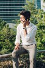 Молодий елегантний бізнесмен розмовляє по телефону на перилах на відкритому повітрі — стокове фото