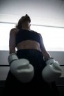 Curly mulher adulta sem rosto em desgaste esporte preto olhando para cima em tons no ginásio — Fotografia de Stock