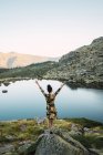 Жінка на скелях маленького озера в горах, вид ззаду — стокове фото
