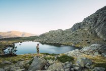 Femme debout sur les rochers du petit lac dans les montagnes — Photo de stock